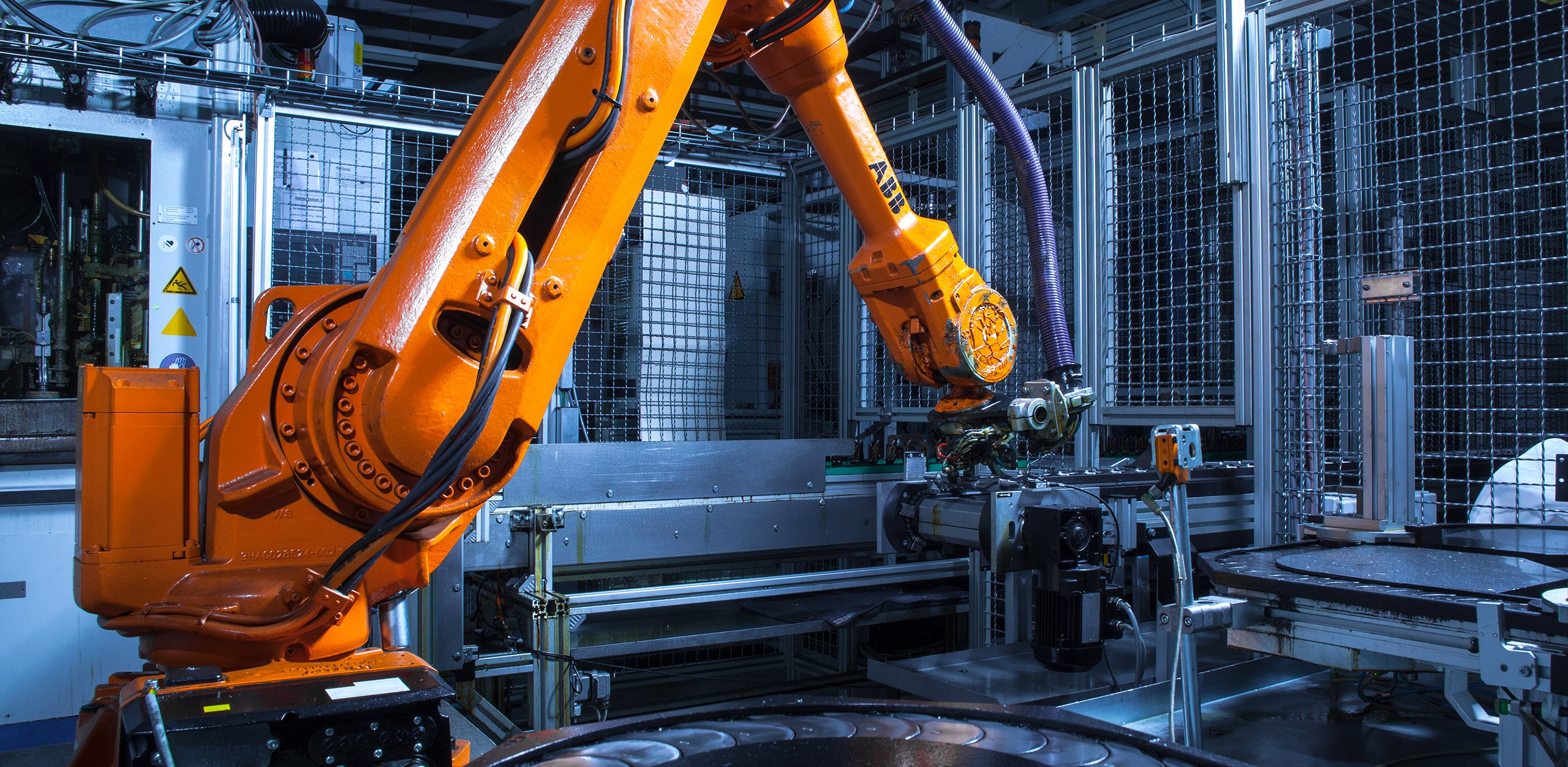 Ein oranger Industrieroboter (ABB IRB 1400) in der Fertigung bei MFT Motoren und Fahrzeugtechnik GmbH.